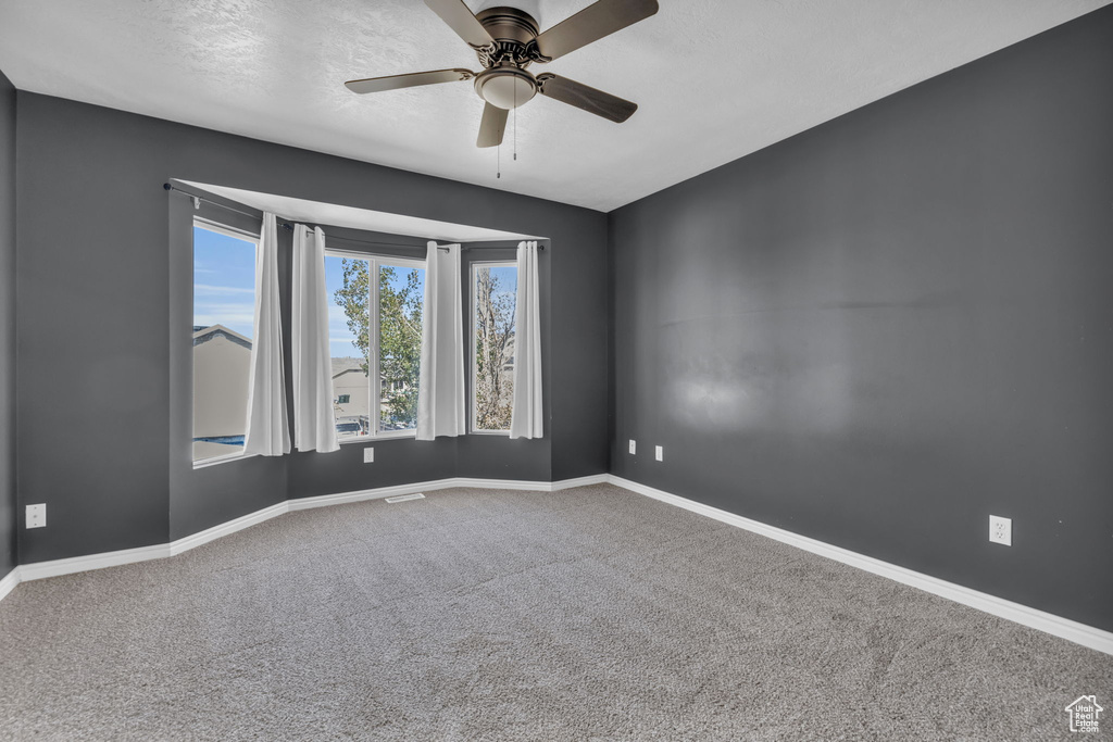 Unfurnished room with ceiling fan, carpet floors, and a textured ceiling