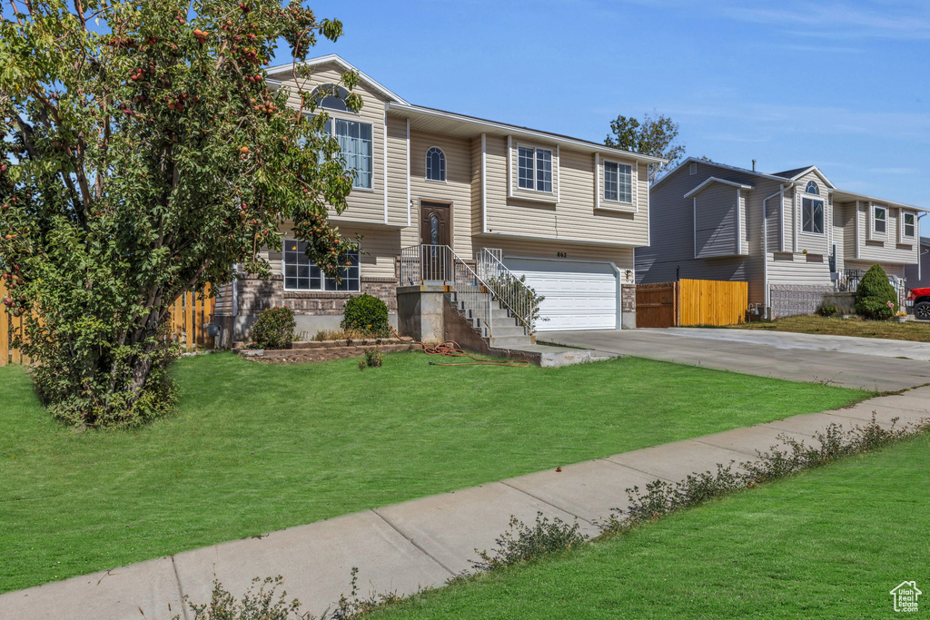 Split foyer home featuring a garage and a front lawn