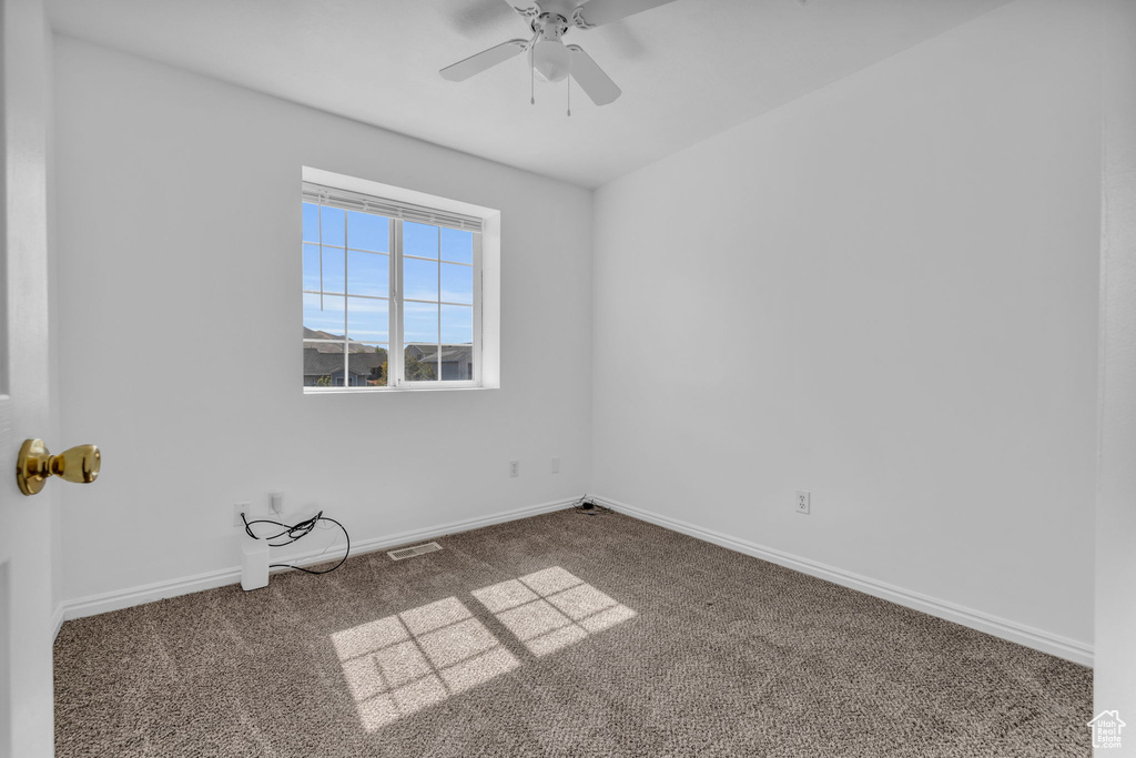 Carpeted empty room featuring ceiling fan