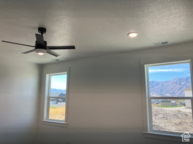 Room details featuring ceiling fan, a mountain view, and a textured ceiling