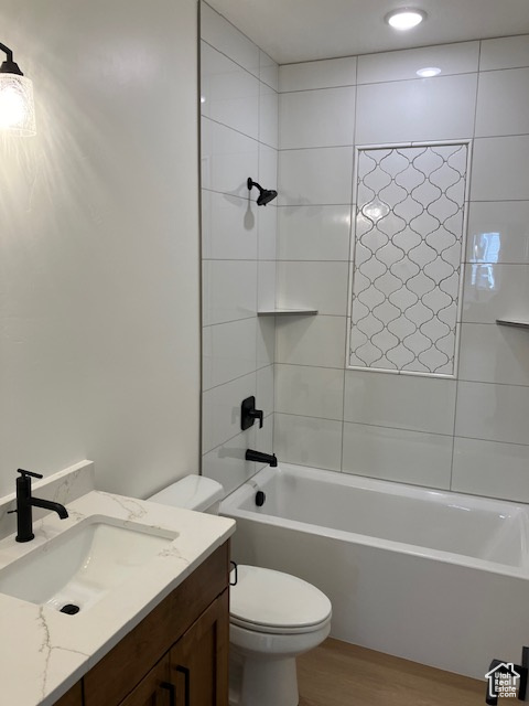 Full bathroom featuring vanity, toilet, wood-type flooring, and tiled shower / bath combo