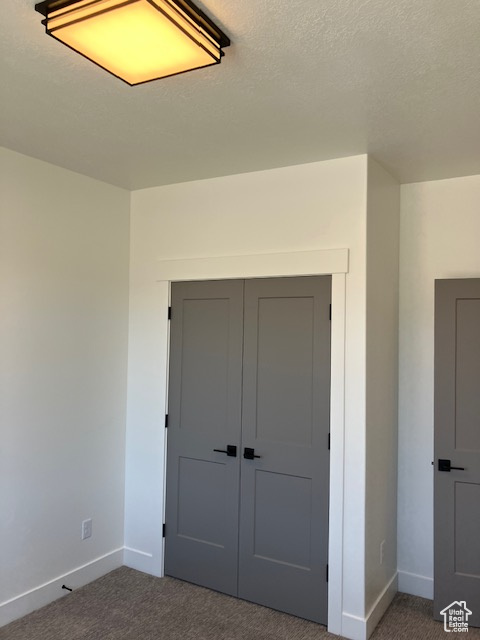 Unfurnished bedroom with a textured ceiling, a closet, and carpet flooring