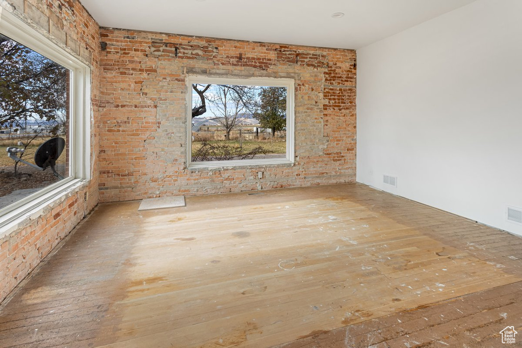 Spare room with brick wall and light hardwood / wood-style flooring