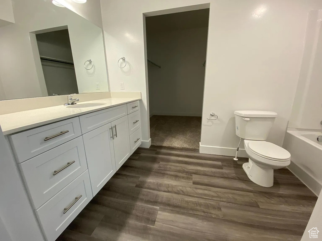 Bathroom featuring a bath, wood-type flooring, vanity, and toilet