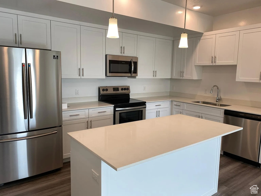 Kitchen featuring white cabinetry, appliances with stainless steel finishes, a kitchen island, and sink