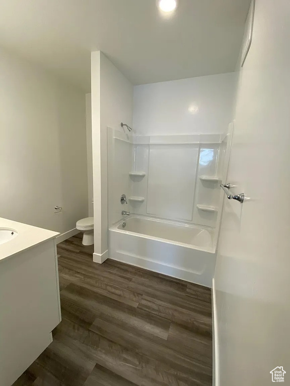 Full bathroom with washtub / shower combination, hardwood / wood-style flooring, vanity, and toilet