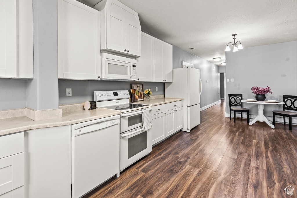 Kitchen with a chandelier, white cabinetry, white appliances, decorative light fixtures, and dark hardwood / wood-style flooring