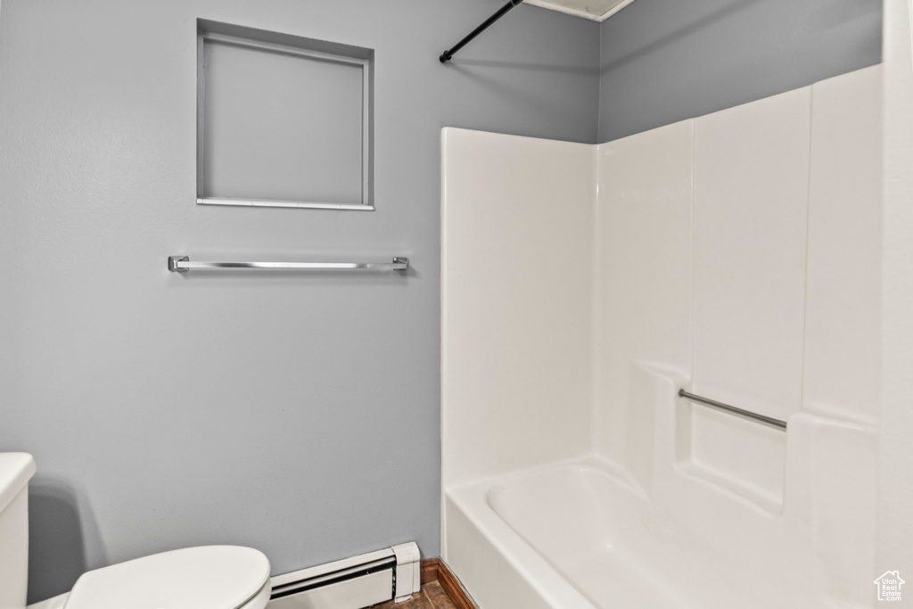 Bathroom with a baseboard radiator, wood-type flooring,  shower combination, and toilet