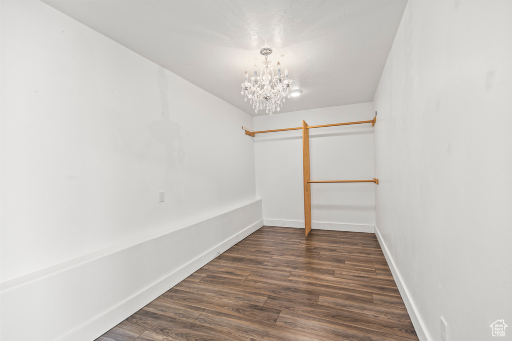 Spacious closet with dark hardwood / wood-style floors and an inviting chandelier