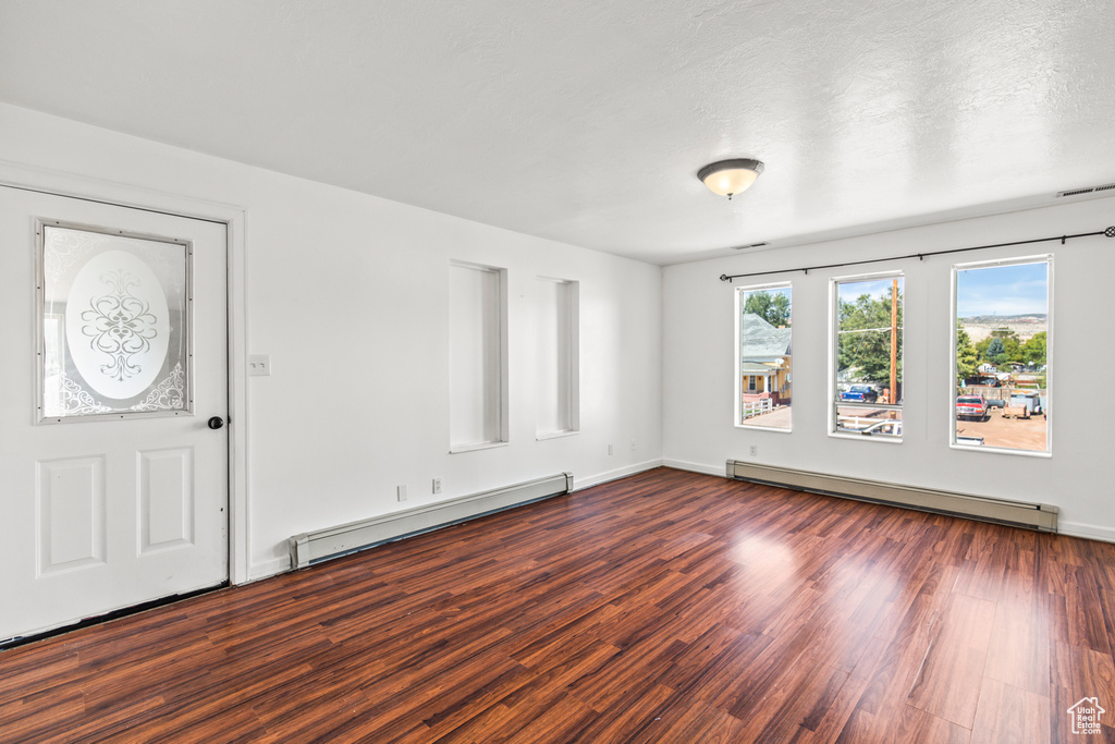 Foyer with a textured ceiling, dark hardwood / wood-style floors, and a baseboard radiator