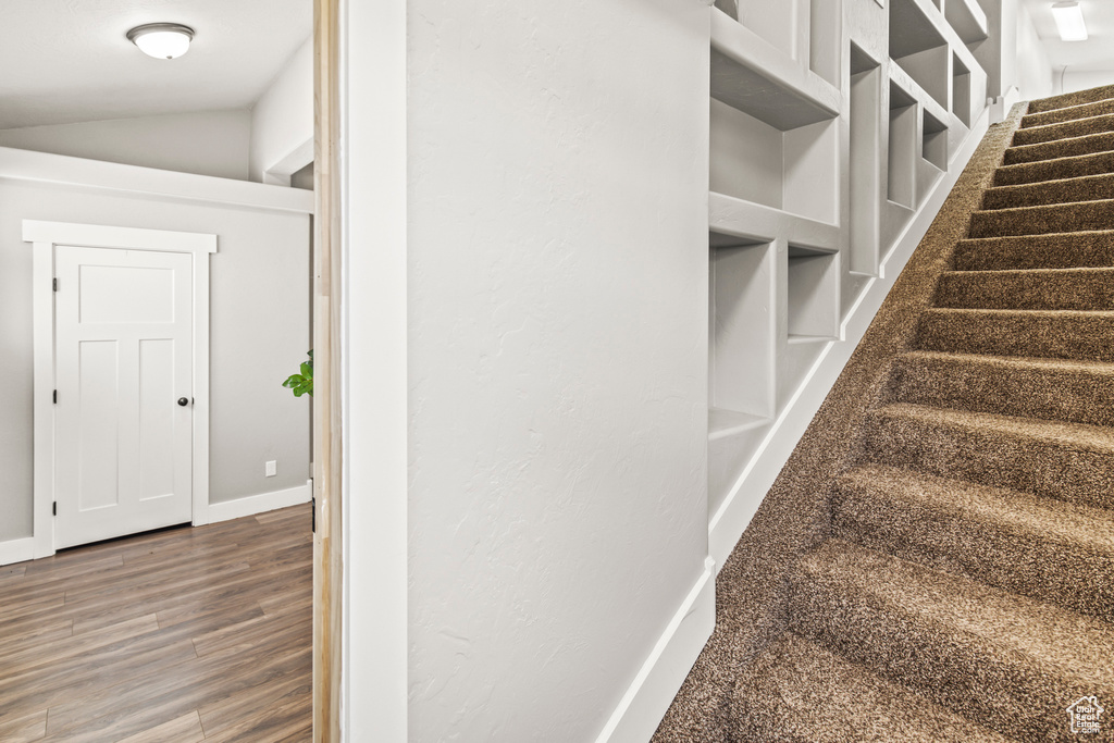 Stairway with hardwood / wood-style flooring and lofted ceiling