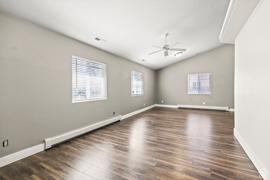 Unfurnished room with lofted ceiling, ceiling fan, baseboard heating, and dark hardwood / wood-style floors