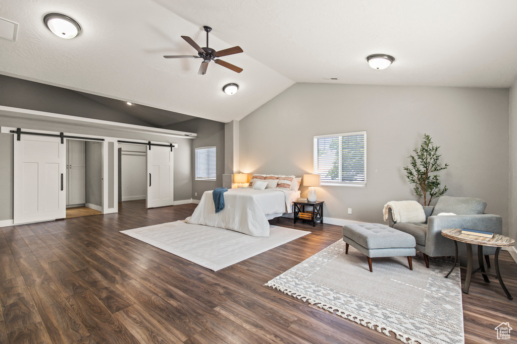 Bedroom featuring a barn door, lofted ceiling, dark wood-type flooring, and ceiling fan