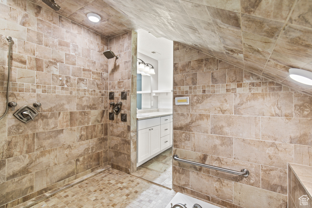 Bathroom with lofted ceiling, vanity, and tiled shower