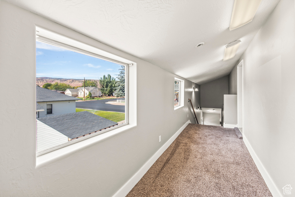 Corridor featuring carpet flooring and vaulted ceiling