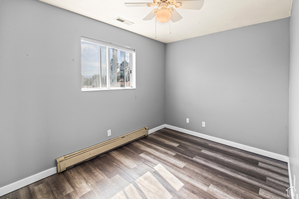 Unfurnished room featuring ceiling fan, a baseboard radiator, and dark hardwood / wood-style floors