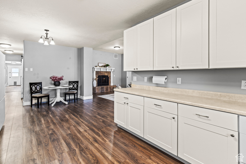 Kitchen with a textured ceiling, dark wood-type flooring, white cabinetry, an inviting chandelier, and decorative light fixtures