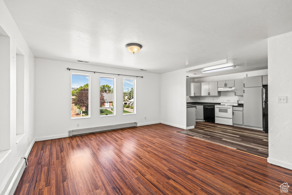 Unfurnished living room featuring a baseboard radiator and dark hardwood / wood-style floors