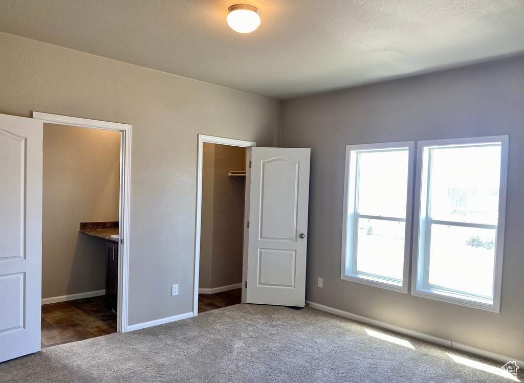 Unfurnished bedroom with ensuite bathroom, a closet, carpet flooring, and a spacious closet