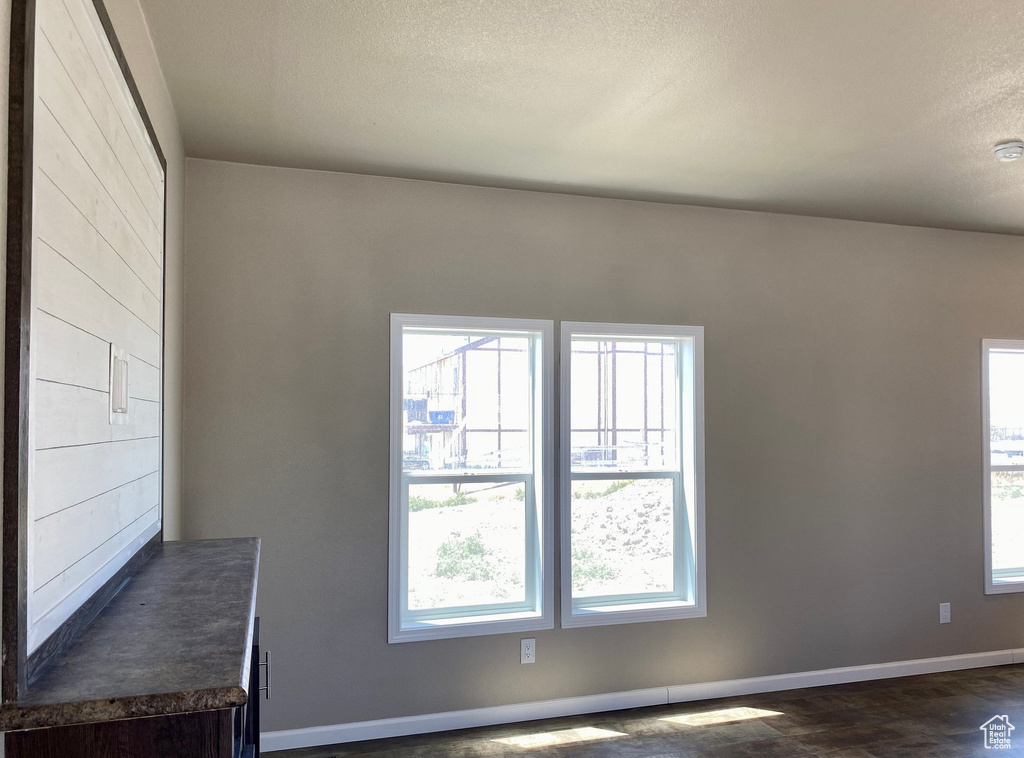 Interior space with a textured ceiling, a healthy amount of sunlight, and dark hardwood / wood-style floors