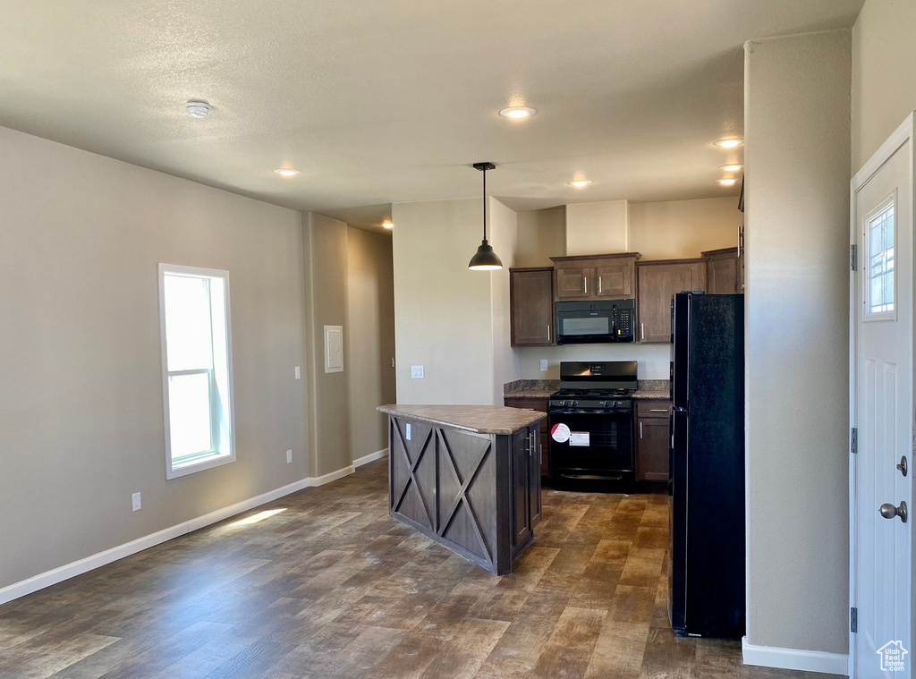 Kitchen with a healthy amount of sunlight, black appliances, a center island, and dark hardwood / wood-style flooring