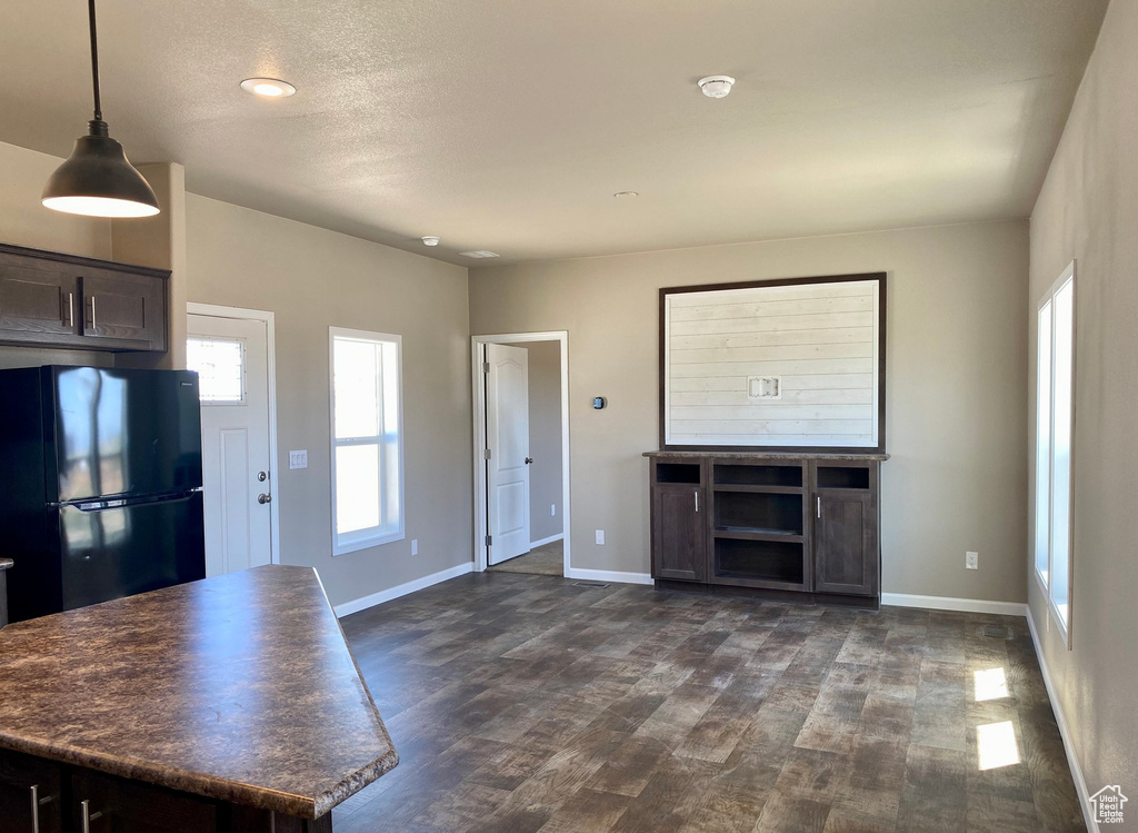 Kitchen with black fridge, dark brown cabinets, a textured ceiling, decorative light fixtures, and dark hardwood / wood-style floors