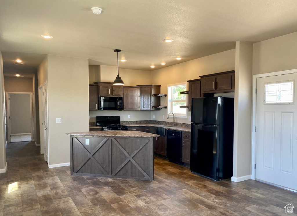 Kitchen with pendant lighting, black appliances, dark brown cabinetry, and dark hardwood / wood-style flooring