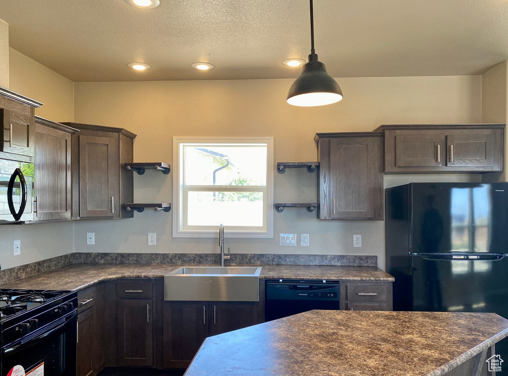 Kitchen featuring dark brown cabinets, a textured ceiling, sink, hanging light fixtures, and black appliances