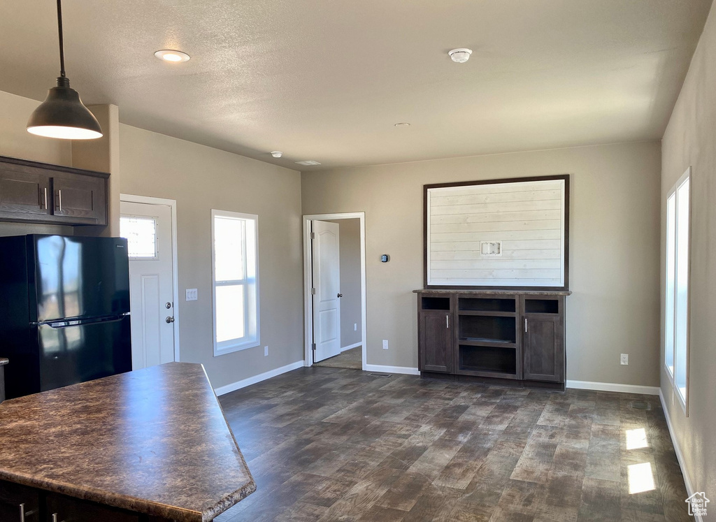 Kitchen featuring black refrigerator, a textured ceiling, dark brown cabinets, decorative light fixtures, and dark hardwood / wood-style floors