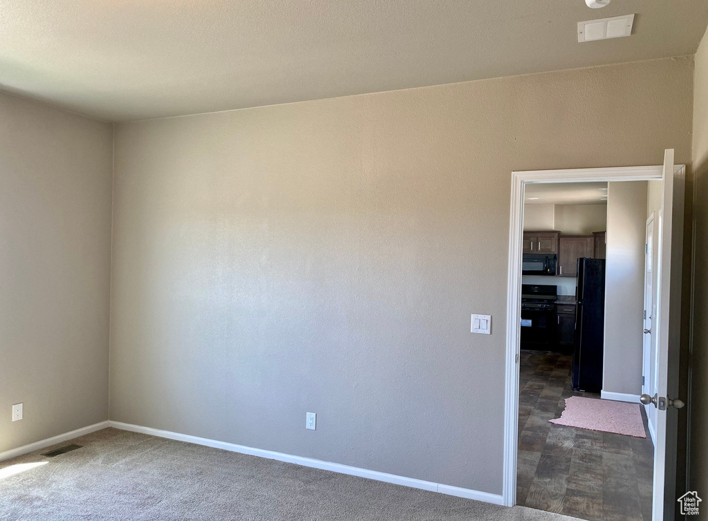 Empty room featuring dark colored carpet