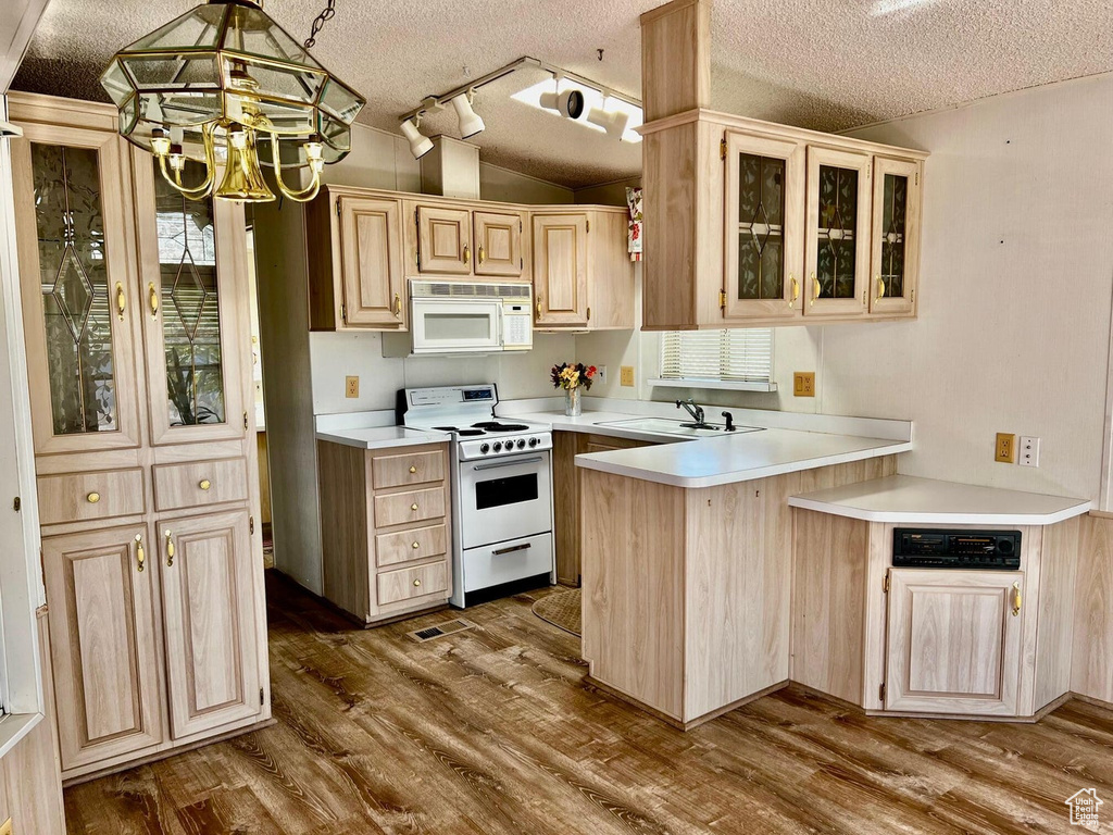 Kitchen with lofted ceiling, hanging light fixtures, kitchen peninsula, white appliances, and a textured ceiling