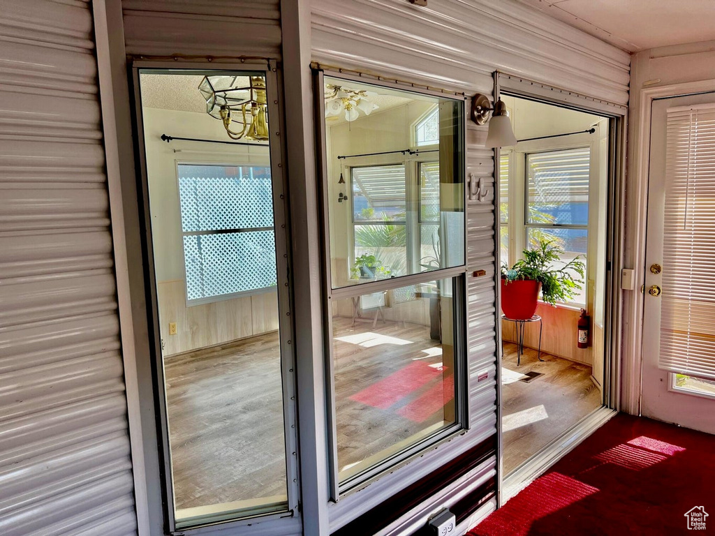 Doorway to outside with an inviting chandelier and hardwood / wood-style flooring