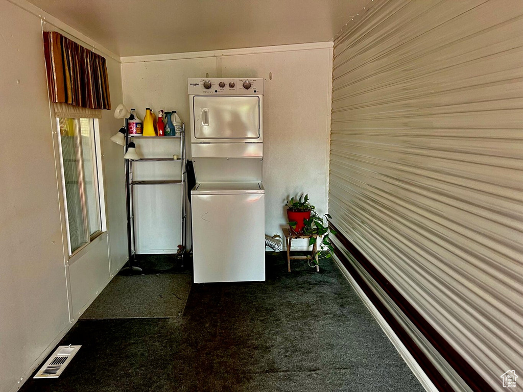 Kitchen featuring stacked washer / dryer and dark colored carpet