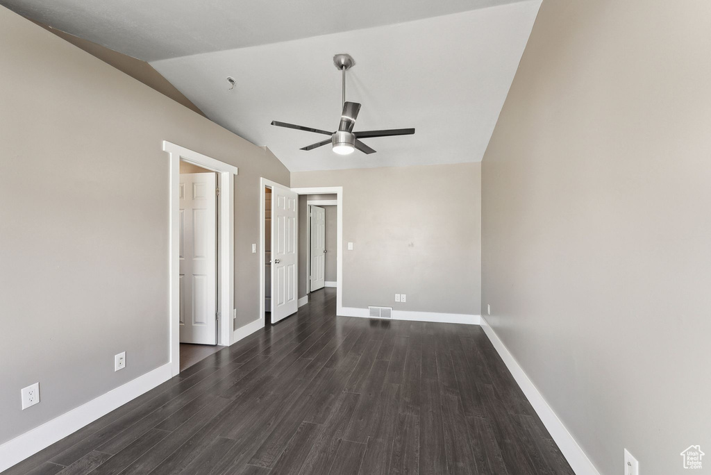 Unfurnished bedroom featuring ceiling fan, vaulted ceiling, and dark hardwood / wood-style flooring