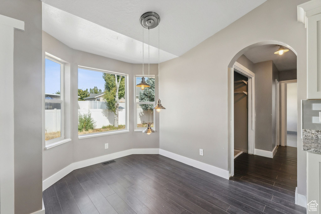 Unfurnished dining area featuring dark wood-type flooring