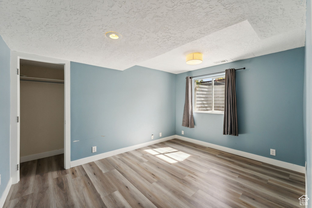 Unfurnished bedroom with a closet, hardwood / wood-style floors, and a textured ceiling