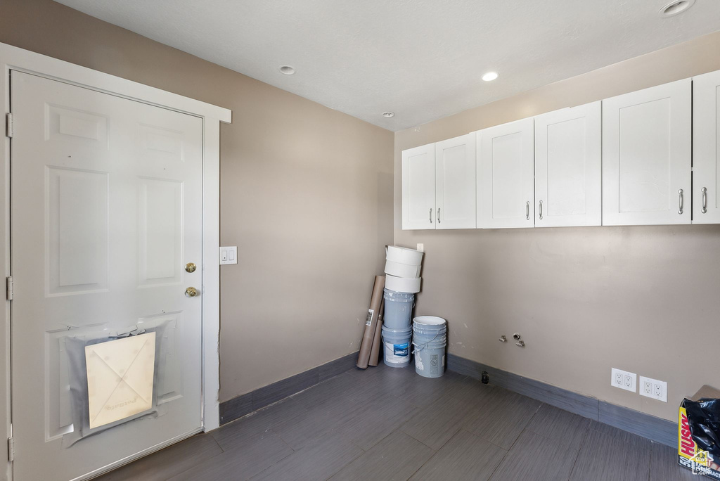 Laundry area with dark hardwood / wood-style floors and cabinets