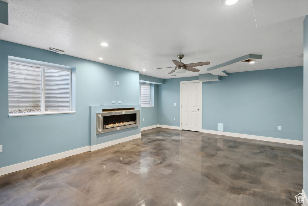 Unfurnished living room with concrete floors and ceiling fan