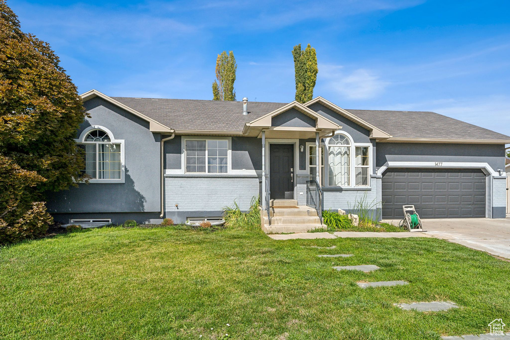 Single story home with a garage and a front yard