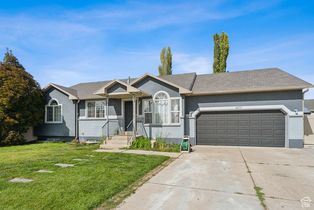 Ranch-style house featuring a garage and a front lawn