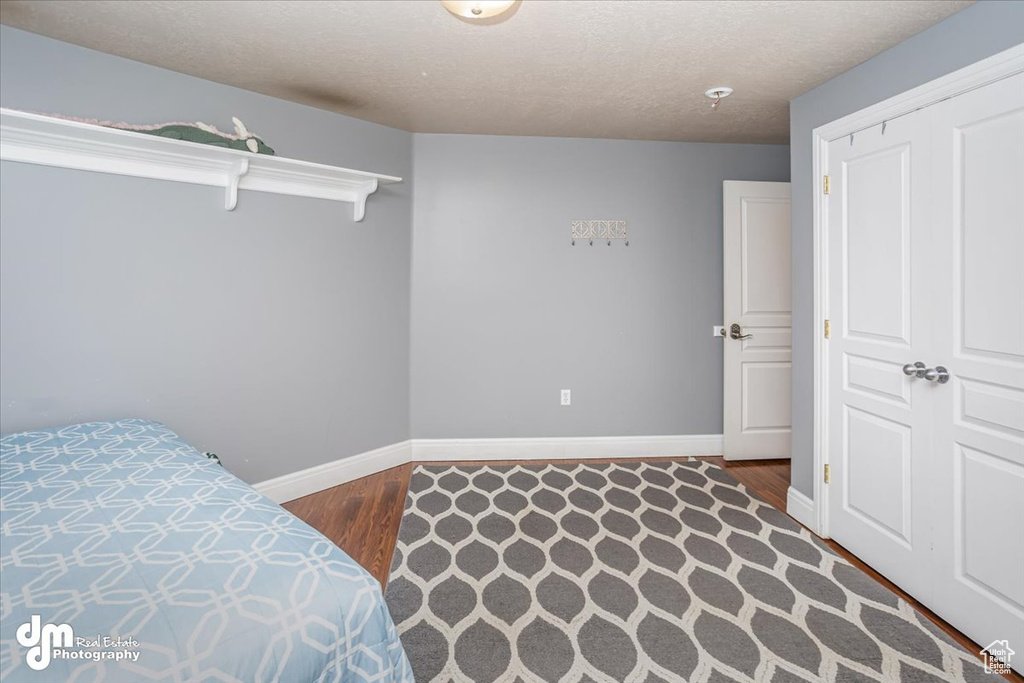 Bedroom featuring a closet, hardwood / wood-style floors, and a textured ceiling