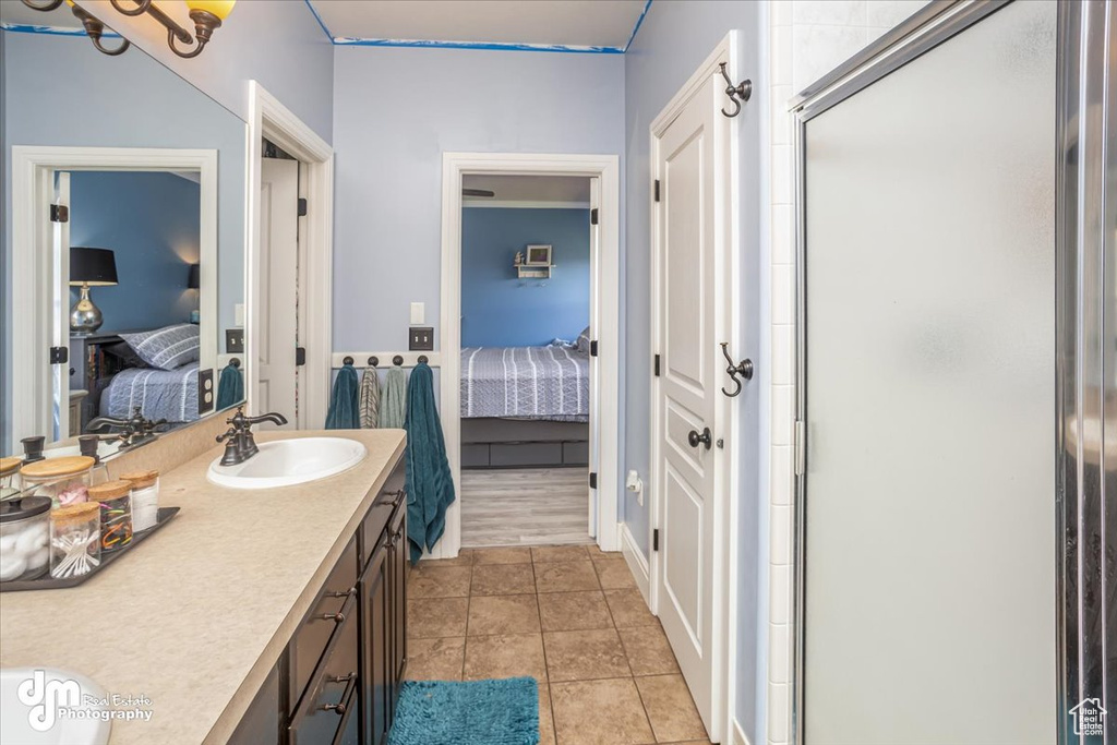 Bathroom with vanity, a shower with shower door, and tile patterned floors