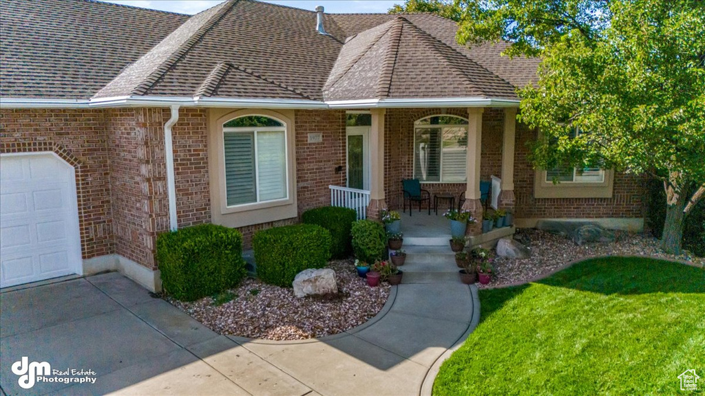 View of front of home featuring a front yard, a garage, and covered porch