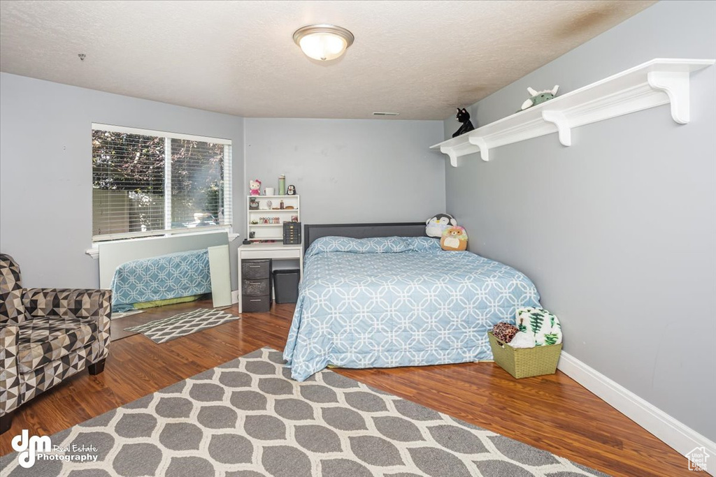 Bedroom with a textured ceiling and hardwood / wood-style floors