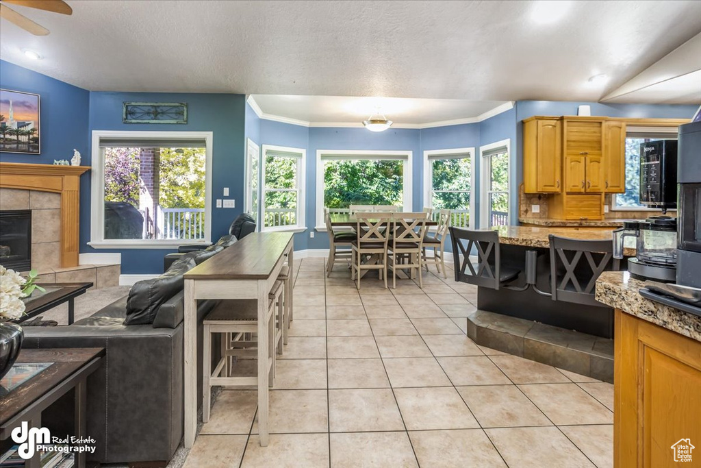 Kitchen with a tile fireplace, light tile patterned flooring, backsplash, ornamental molding, and ceiling fan