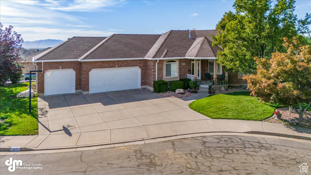 View of front of house featuring a front yard, a mountain view, a garage, and a porch