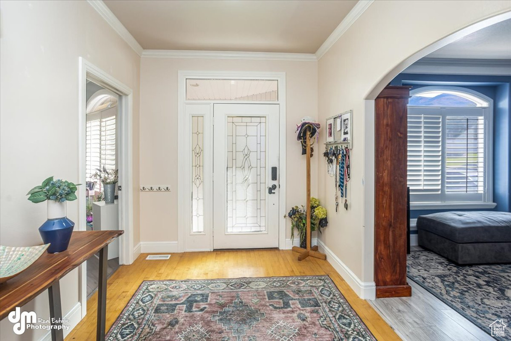 Entrance foyer featuring a healthy amount of sunlight, light hardwood / wood-style floors, and ornamental molding