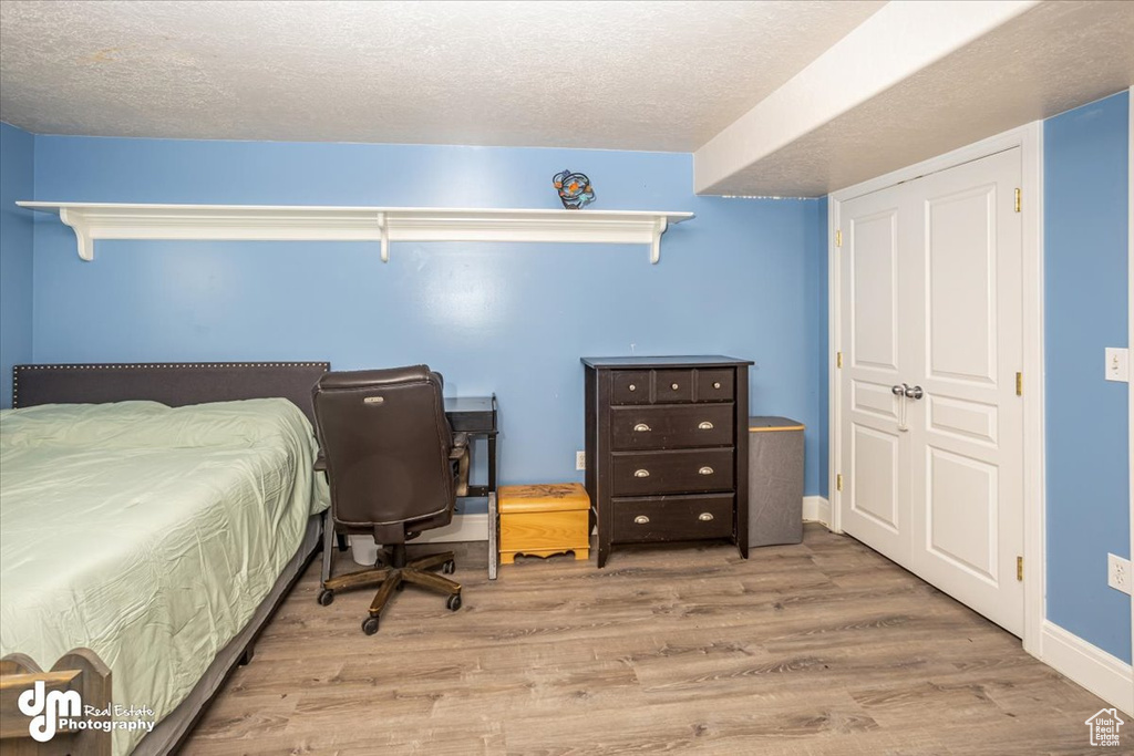 Bedroom with a textured ceiling and light hardwood / wood-style floors