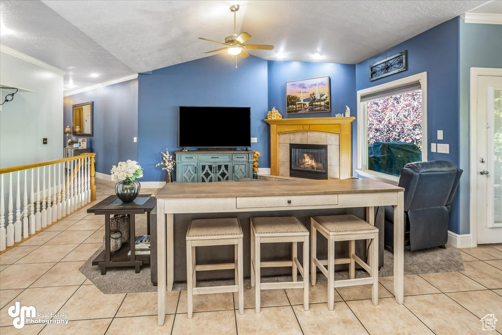 Living room with vaulted ceiling, ceiling fan, a fireplace, and light tile patterned floors