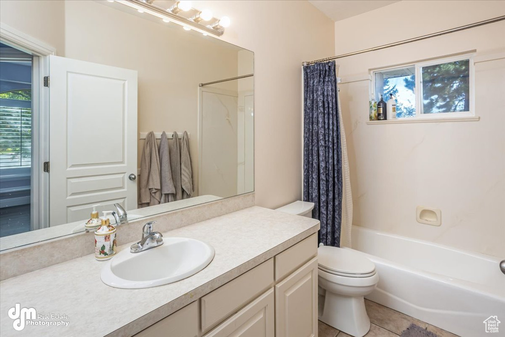 Full bathroom featuring vanity, toilet, shower / bath combo with shower curtain, and tile patterned floors